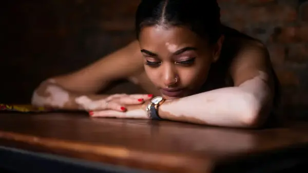 woman in red and white floral dress lying on brown wooden table
