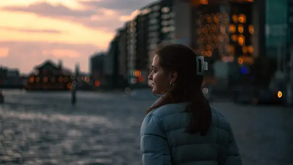 Woman looking out at a city waterfront at dusk