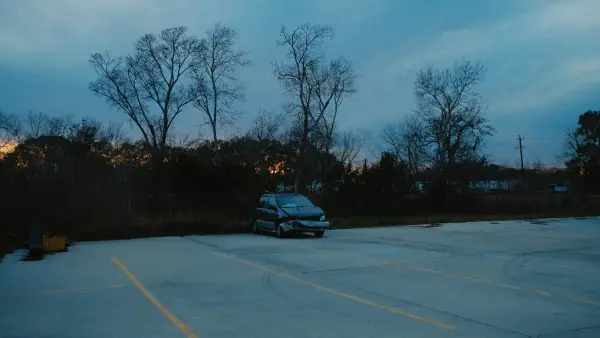 A car parked in an empty lot at dusk.