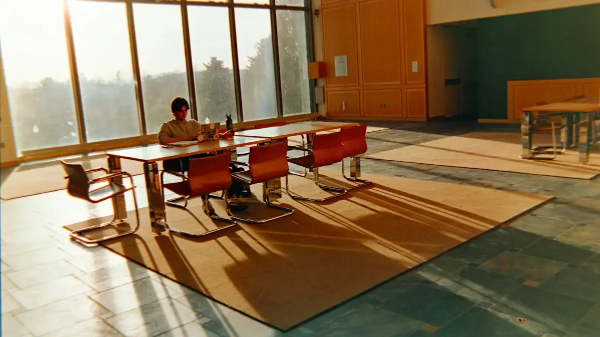 Man sitting at table with large windows and sunbeams.