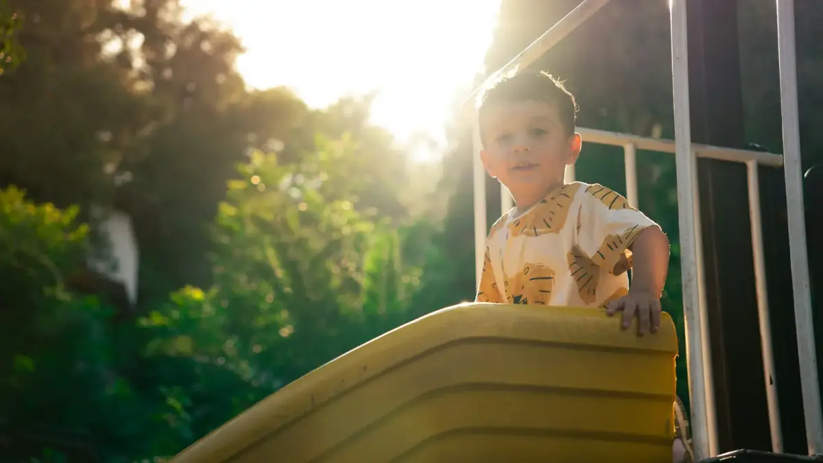 A happy child plays on a playground slide.