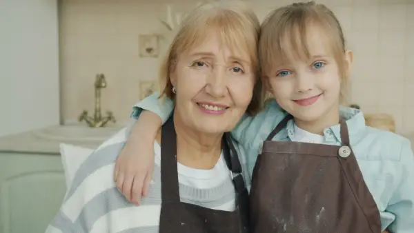 Grandmother and granddaughter smiling in the kitchen.