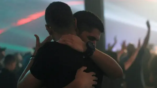two men hugging each other inside bar