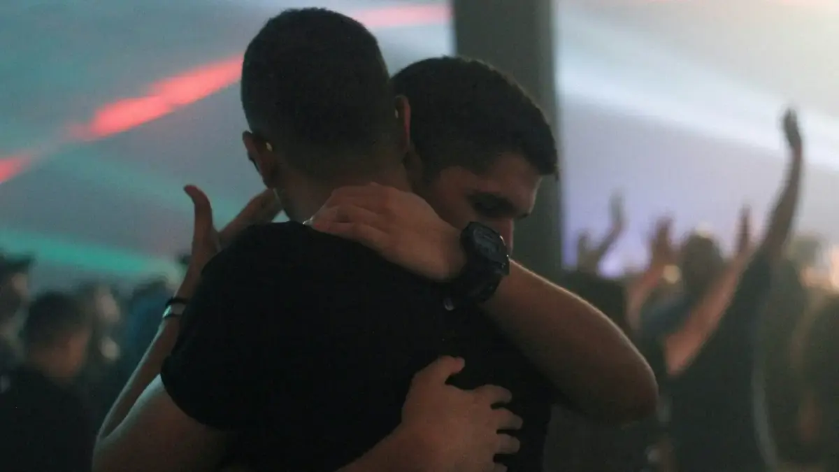 two men hugging each other inside bar