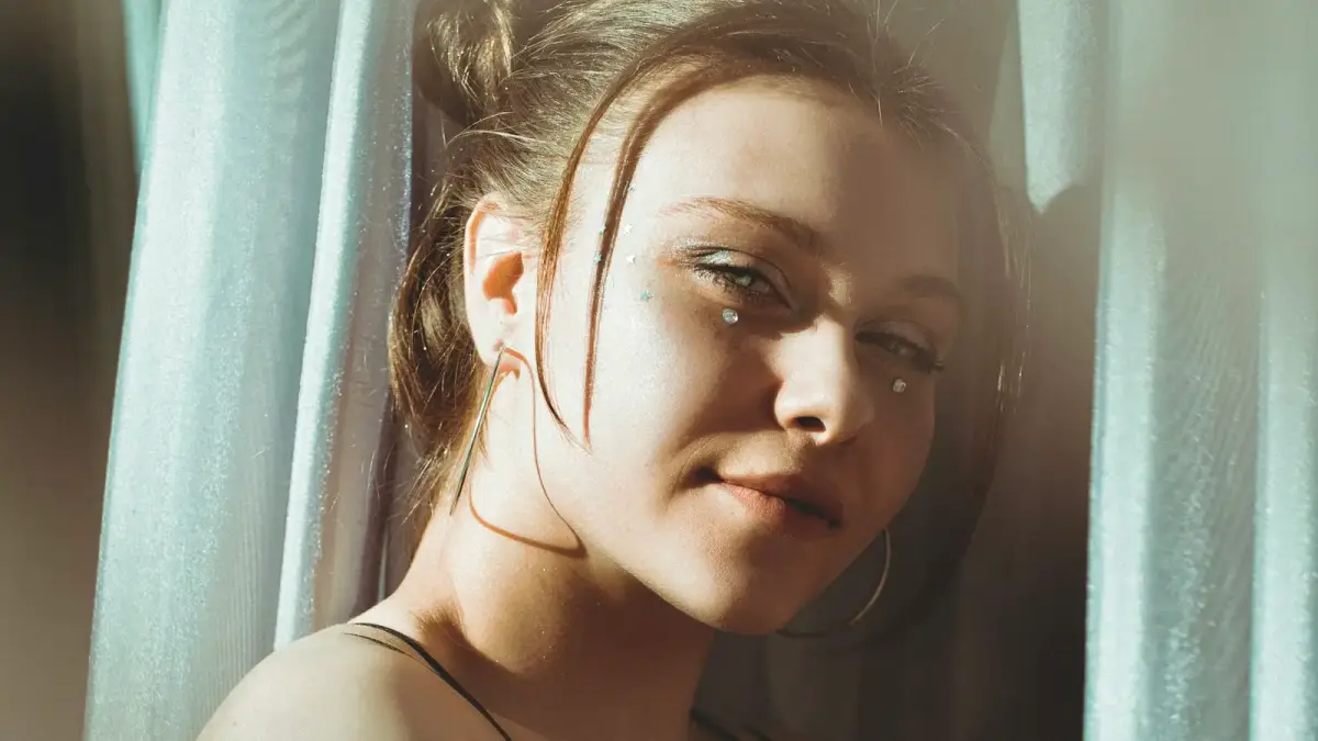 a woman with a hoop earring standing in front of a curtain