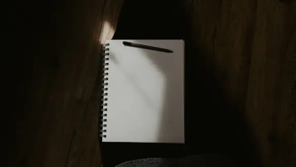 white spiral notebook on black textile