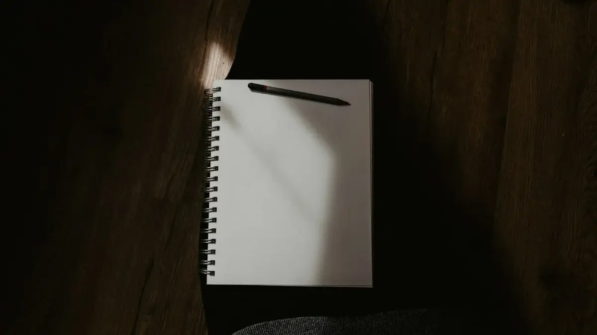 white spiral notebook on black textile