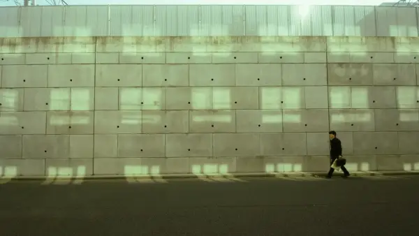 Man walking along a concrete wall with light patterns