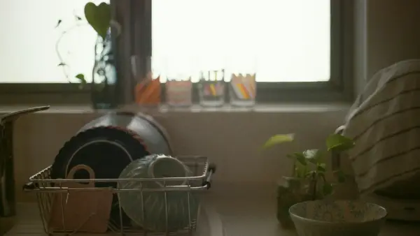 a kitchen counter with dishes in a basket next to a window