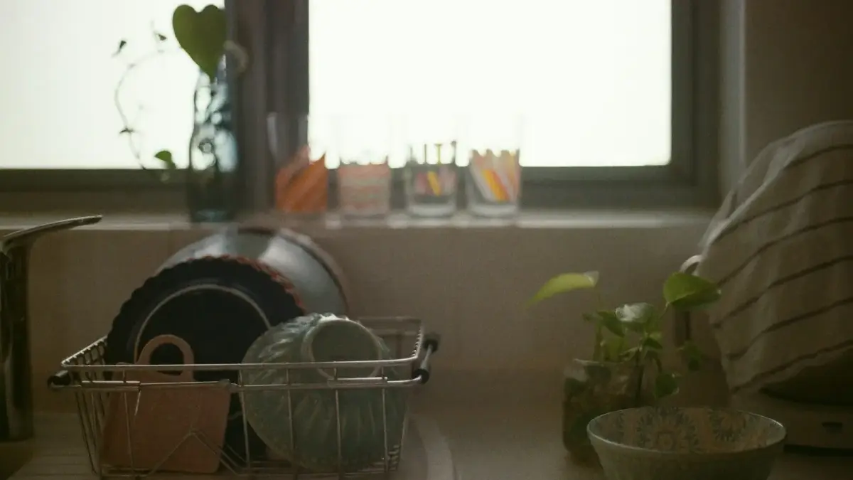 a kitchen counter with dishes in a basket next to a window
