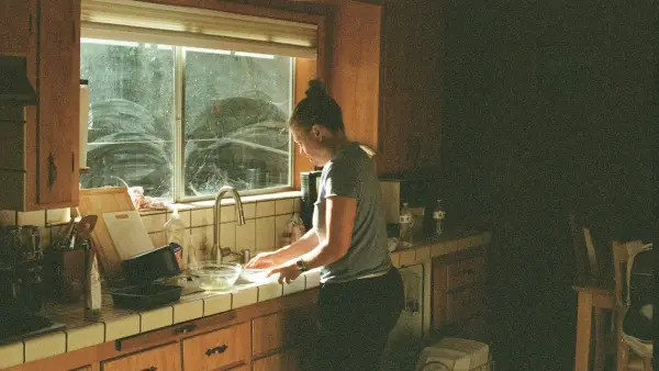 Woman washing dishes at a kitchen sink.