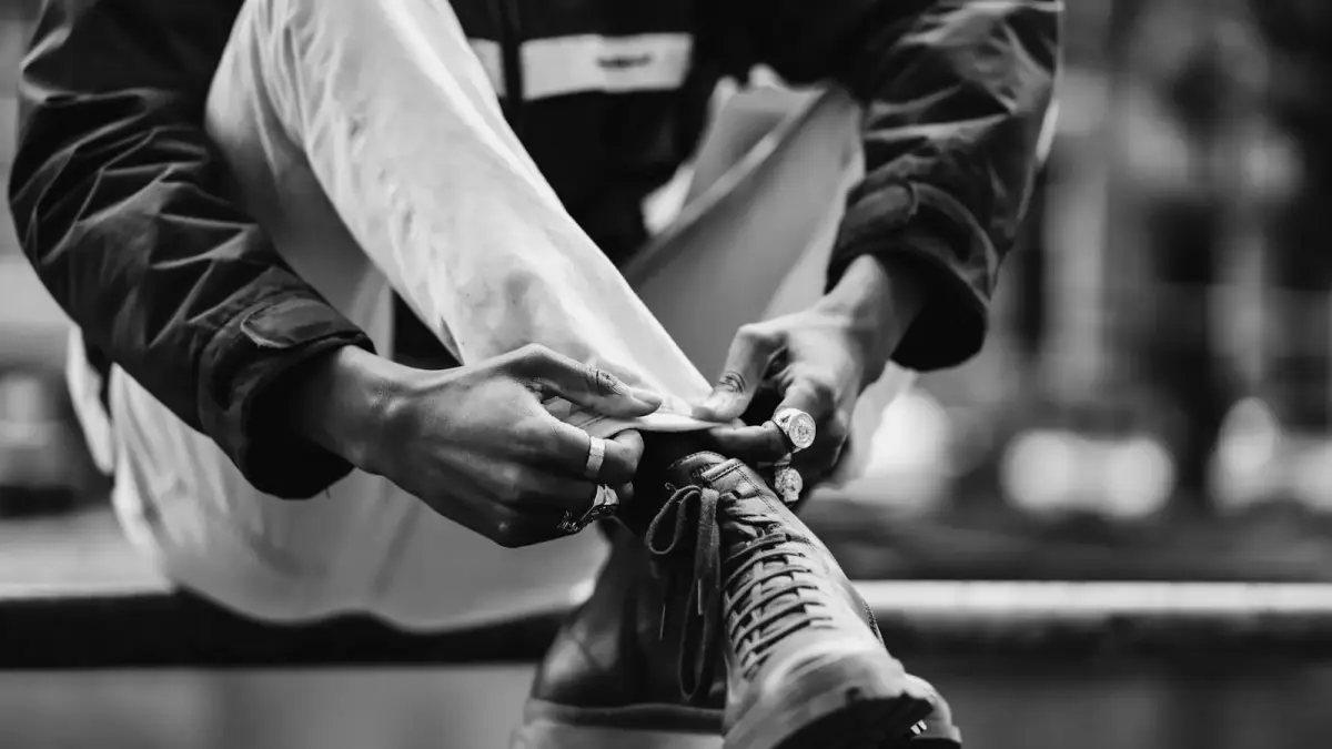 a black and white photo of a man tying his shoes