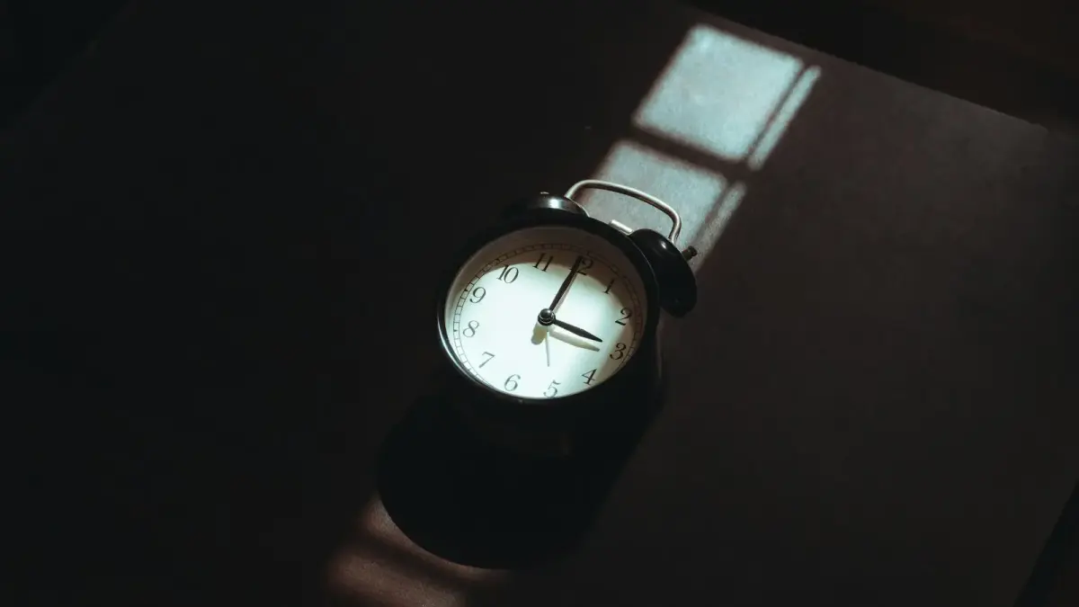 Alarm clock casting a shadow on a dark surface