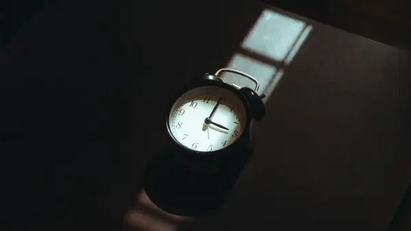 Alarm clock casting a shadow on a dark surface