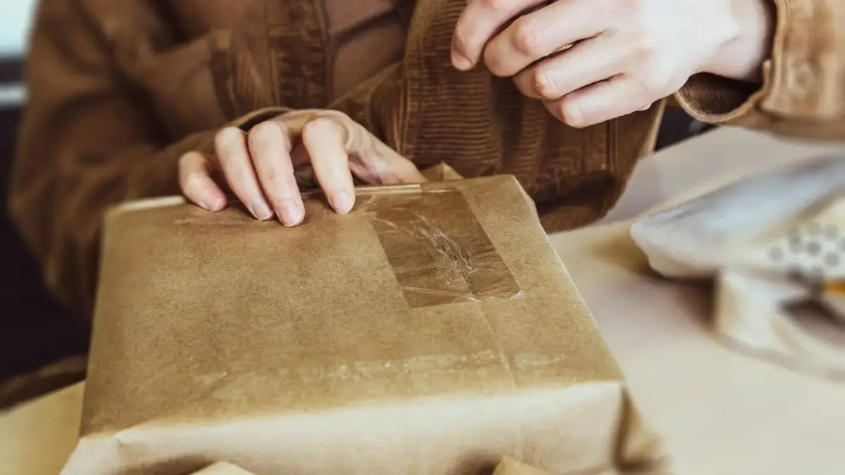 a person holding a brown paper bag on top of a table