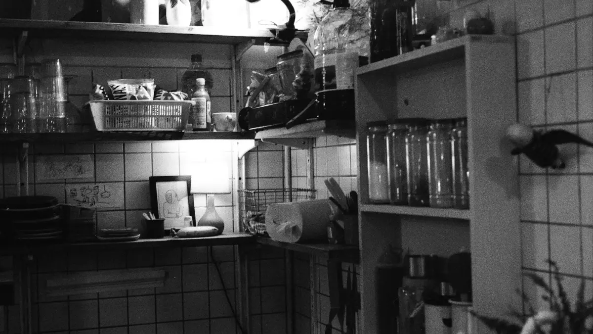 A cluttered kitchen shelf with jars and utensils.