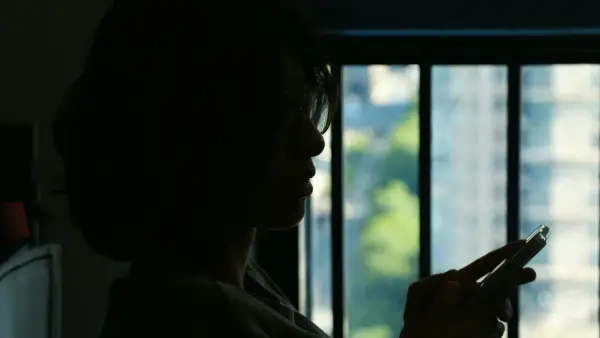 Silhouette of a woman holding a cigarette by the window