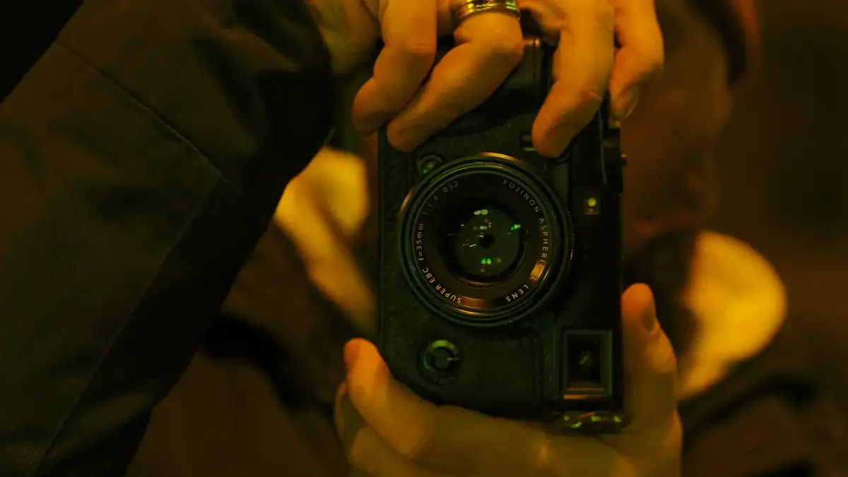 Hands holding a vintage camera, taking a picture.