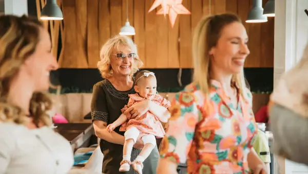 a group of women standing around each other holding a baby