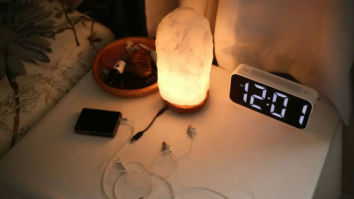 Nightstand with a lamp, clock, and chargers