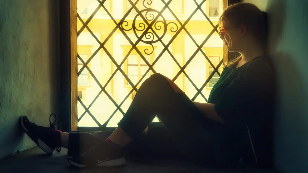 a woman sitting on the floor in front of a window