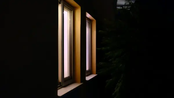 Two lit windows on a dark building exterior.