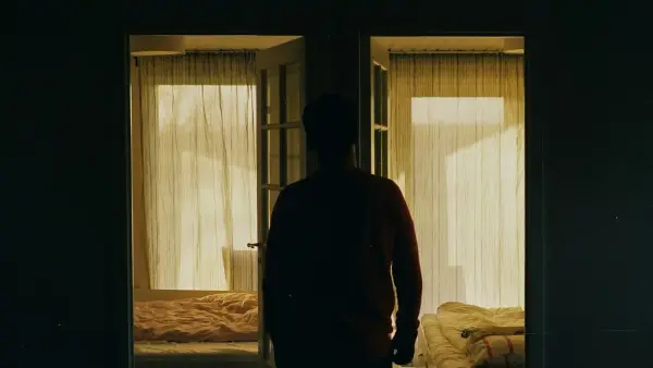 man in red long sleeve shirt standing near window