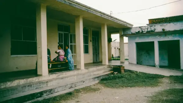 Two people sit on a bench outside a building