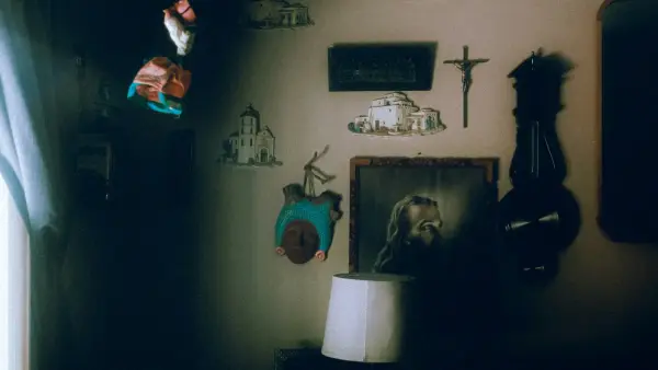 Religious decorations, clock, and lamp on a dark, shadowed wall