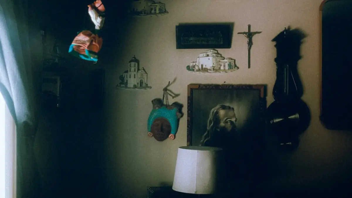 Religious decorations, clock, and lamp on a dark, shadowed wall