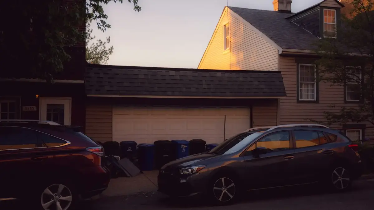 Residential street with parked cars and houses at sunset.