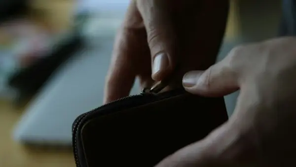 a person opening a wallet on a table