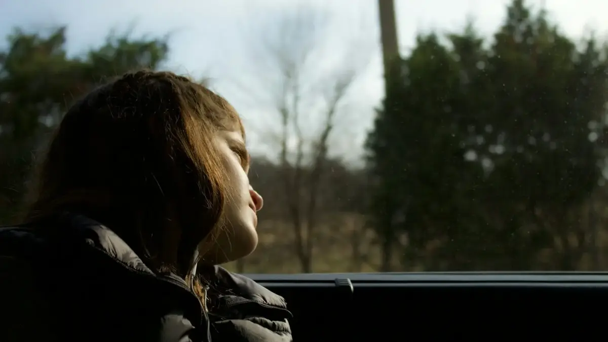 a young girl sitting in a car looking out the window
