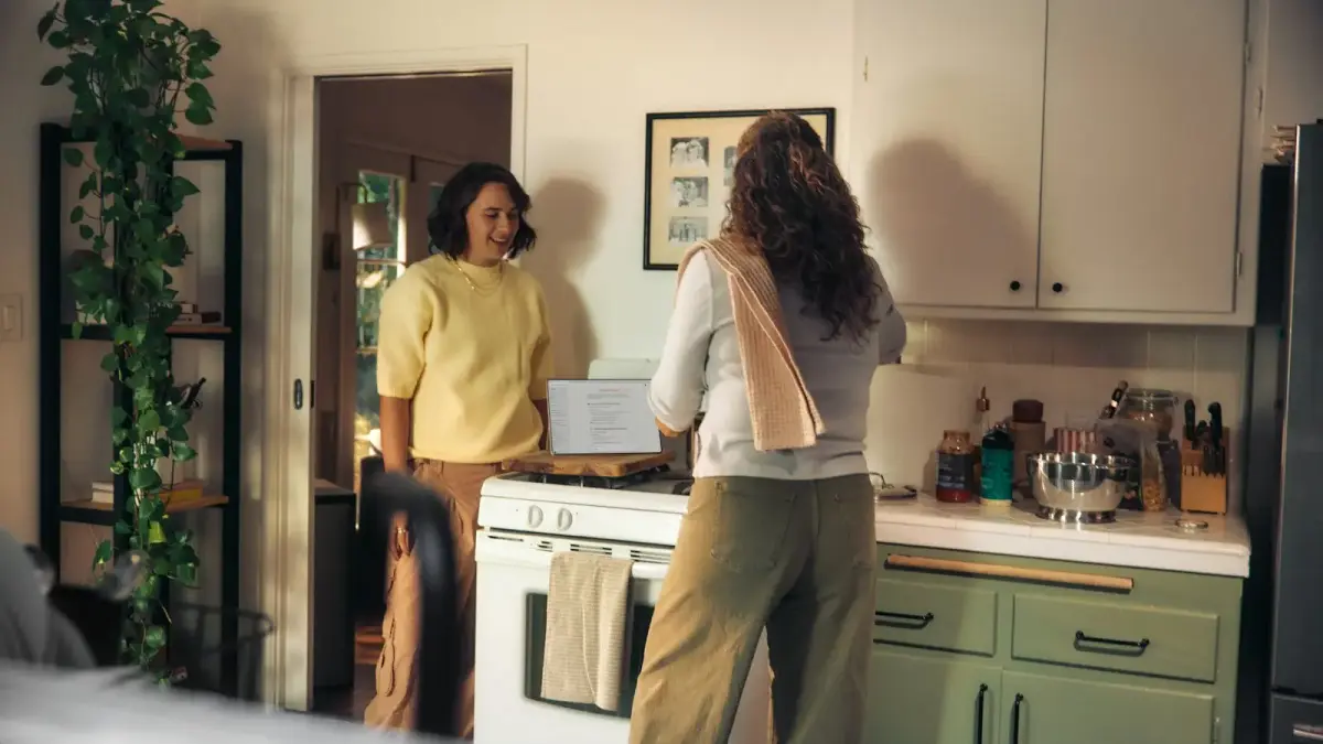 Two women talking in a kitchen while cooking