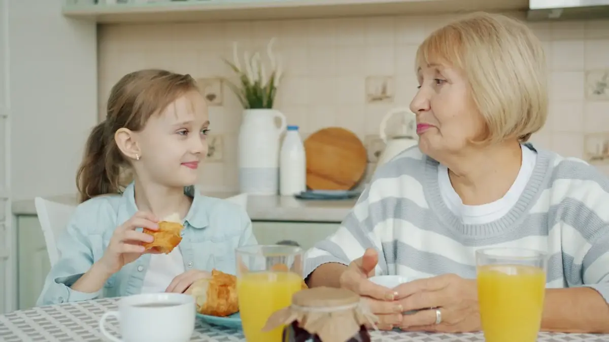 Grandmother and granddaughter sharing breakfast at table