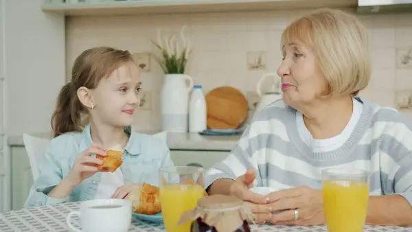 Grandmother and granddaughter sharing breakfast at table