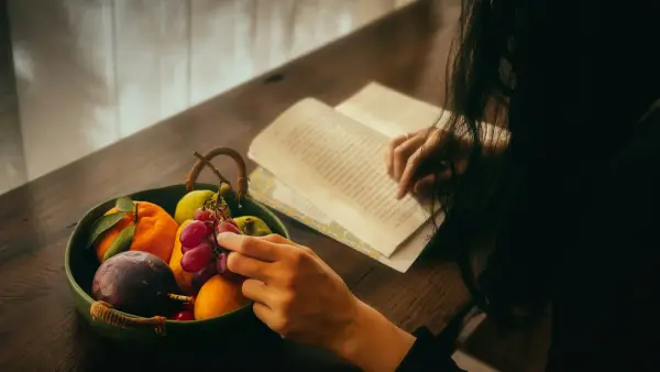 Person reading by a bowl of fruit