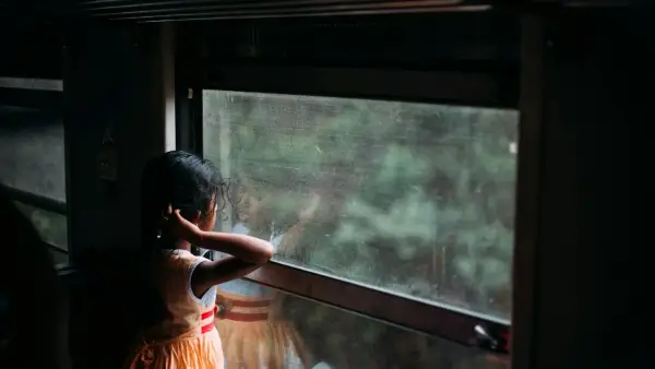 girl in orange sleeveless dress looking at the window