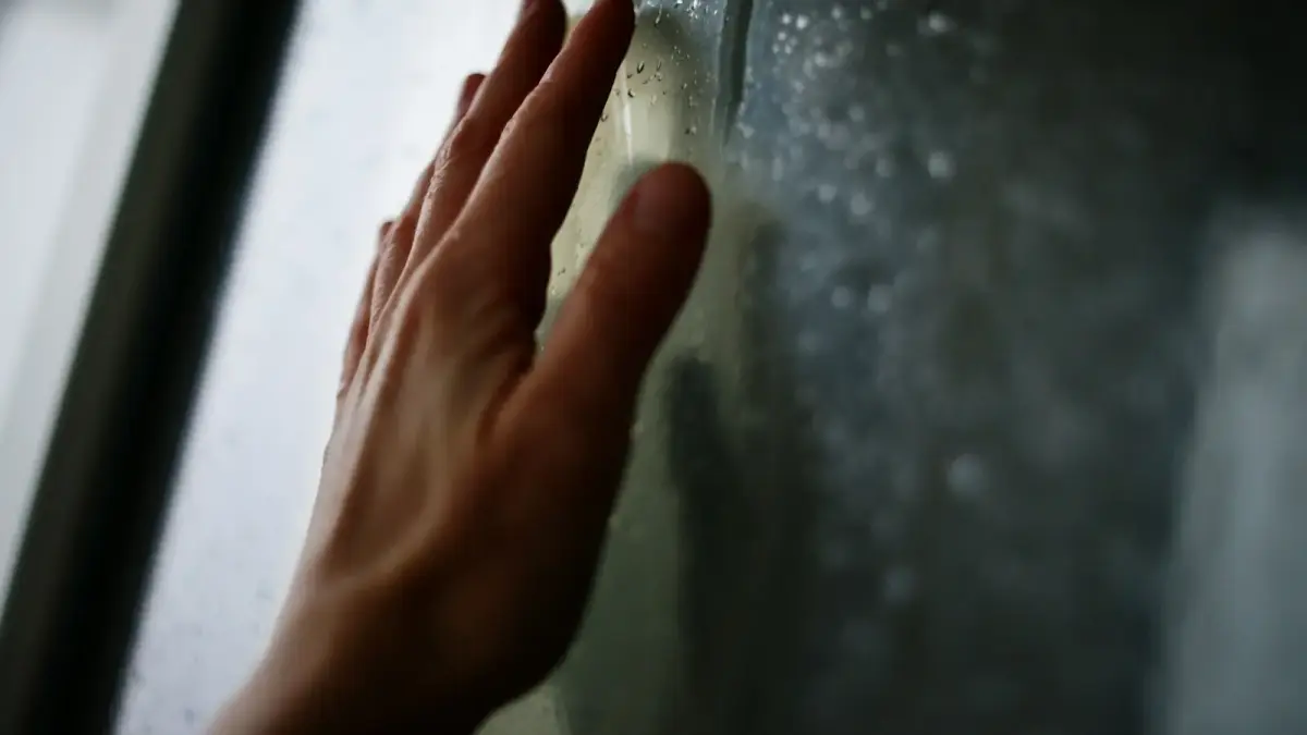 Hand rests against a foggy window