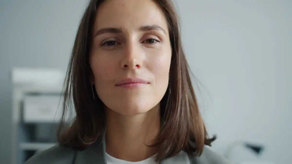 A woman with brown hair wearing a gray blazer