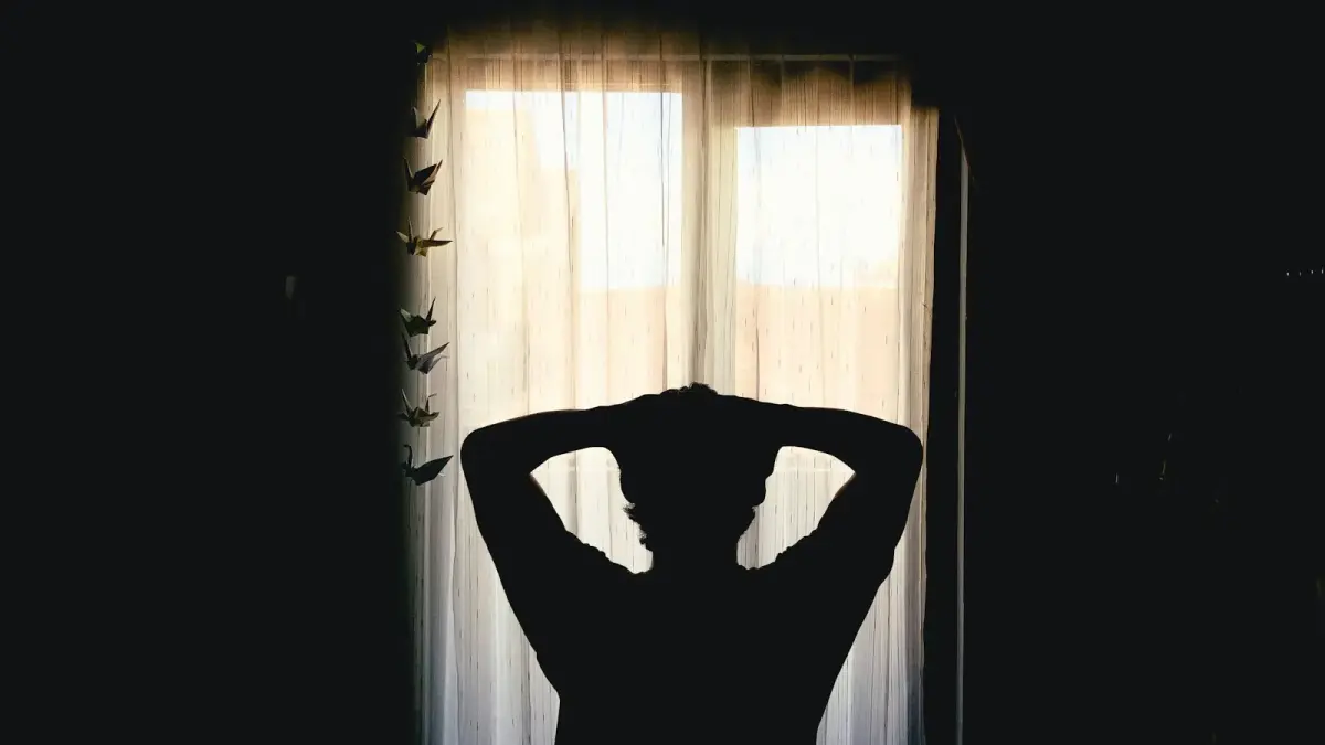 Silhouette of a person with hands behind head