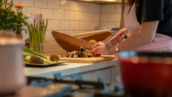 a woman in a kitchen chopping vegetables on a cutting board