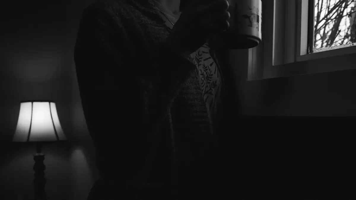 Person holding a mug by a window