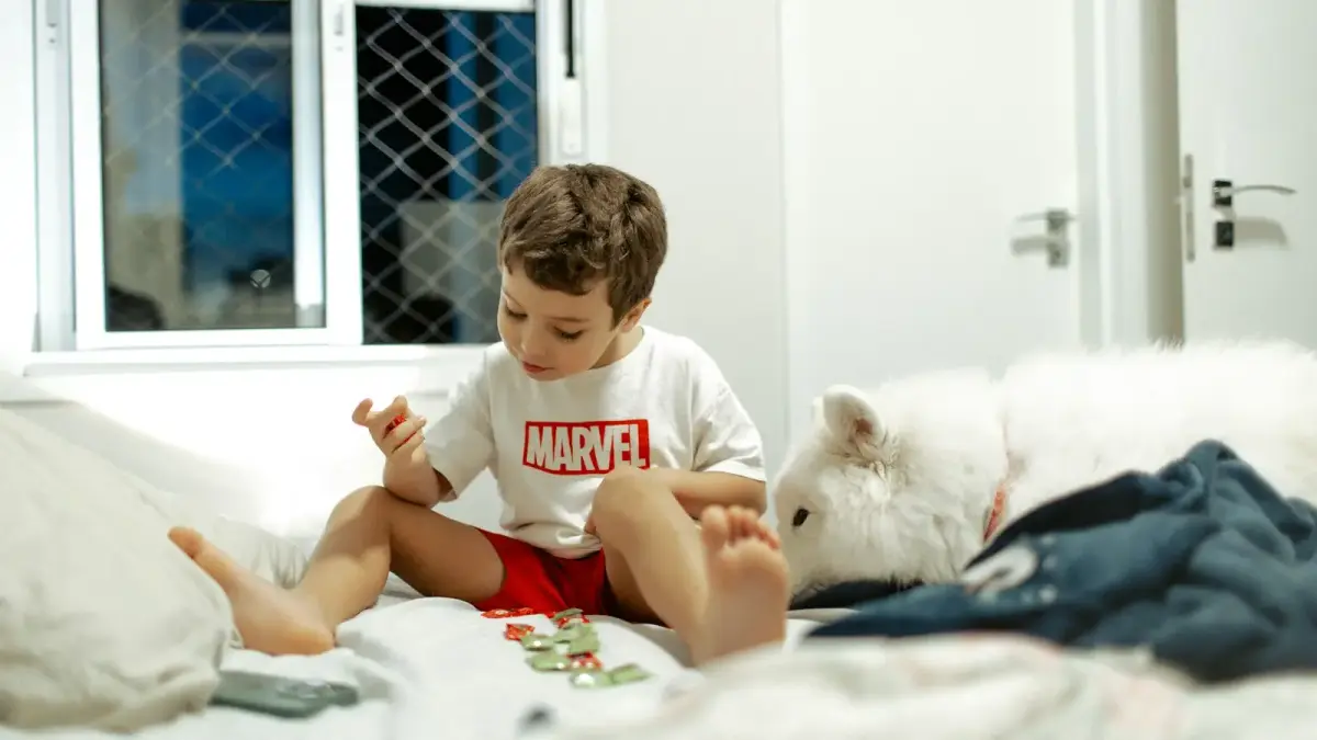 Young boy playing with toys on a bed.