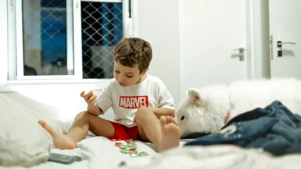 Young boy playing with toys on a bed.