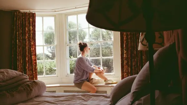 Woman looking out a large bay window