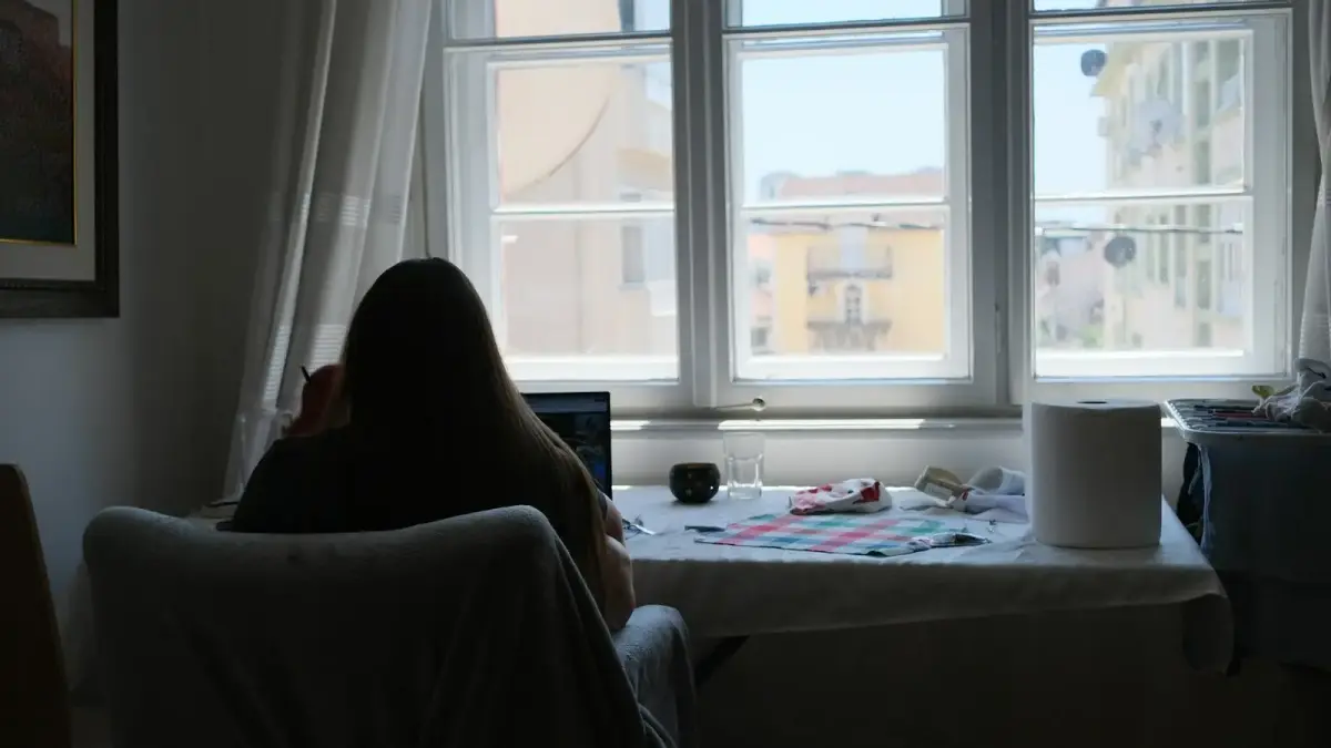 Person works near a bright window in a room.