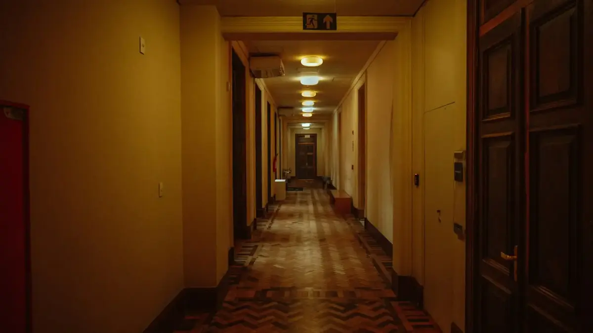 Long, dimly lit hotel hallway with doors on the sides