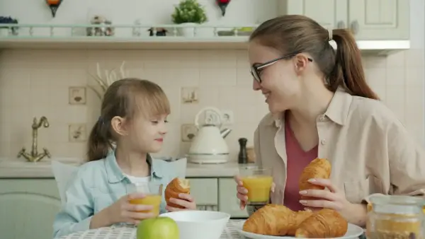 Mother and daughter enjoying breakfast with croissants.