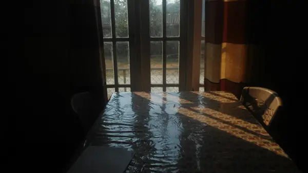 Sunlight streams across a table with chairs.